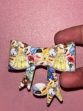 Light-colored bow featuring Belle, Mrs. Potts, the Beast, Cogsworth, red roses, and rose petals