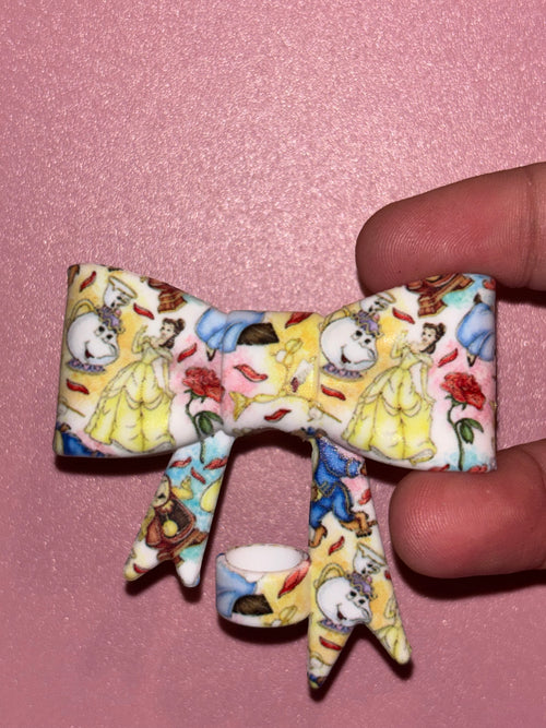 Light-colored bow featuring Belle, Mrs. Potts, the Beast, Cogsworth, red roses, and rose petals